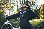 Forest, fitness and cyclist with back pain, bicycle and exercise adventure trail in nature. Cycling, woods and man with injury, mountain bike and muscle ache for workout, motivation or healthcare.