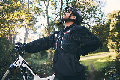 Buy stock photo Forest, fitness and cyclist with back pain, bicycle and exercise adventure trail in nature. Cycling, woods and man with injury, mountain bike and muscle ache for workout, motivation or healthcare.