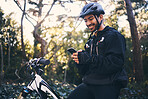 Sports, man and phone outdoor for mountain bike, cycling or workout and smile in nature. Male person in forest with smartphone in hands for communication, gps travel app or fitness with safety gear