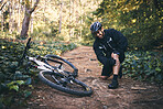 Sports man, injury and leg pain outdoor while cycling on mountain bike with nature trees and dirt. Athlete person on ground in forest for fitness exercise, training or workout accident, crash or fall