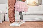 Feet of father and child dancing in the living room of their modern family home to music or radio. Dance, energy and closeup of man bonding, having fun and standing with his daughter in their house.