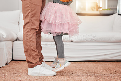 Buy stock photo Feet of father and child dancing in the living room of their modern family home to music or radio. Dance, energy and closeup of man bonding, having fun and standing with his daughter in their house.