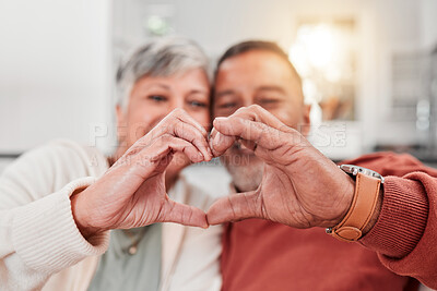 Buy stock photo Couple, senior and heart hands in home, love and bonding in retirement together. Romance, hand gesture and elderly man and woman with emoji for care, affection and empathy, commitment and trust.