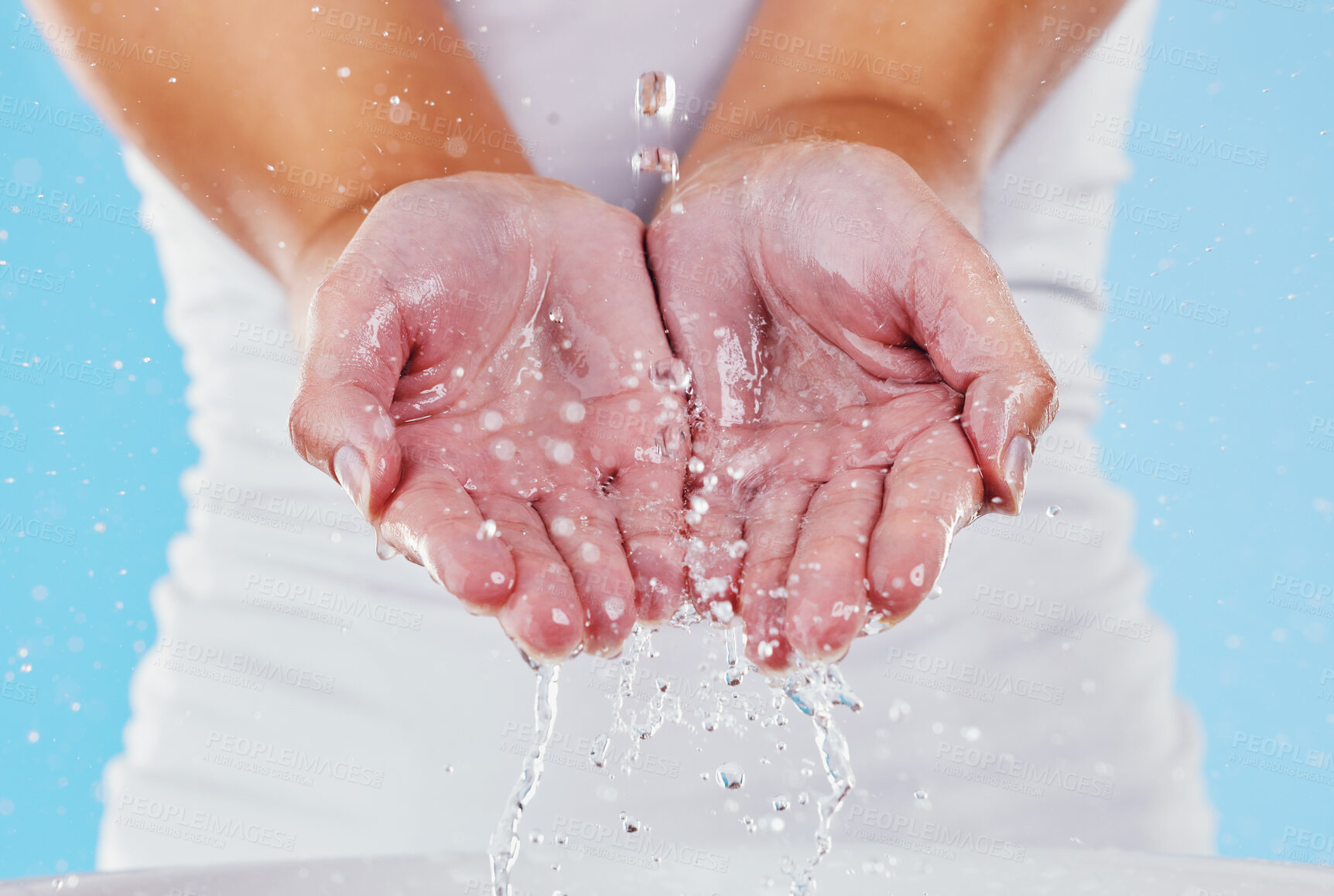 Buy stock photo Water, washing and splash with hands of woman in studio for beauty, sustainability and skincare. Shower, cleaning and cosmetics with female in blue background for self care, spa and disinfection