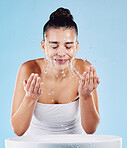 Sink, face water splash and skincare of a woman cleaning for natural beauty and facial wellness. Isolated, blue background and studio with a female model doing dermatology and cosmetic routine