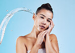 Portrait, beauty and woman with water splash, cosmetics and cleaning against a blue studio background. Face, female model and person with drops, wellness and morning routine for self care and health