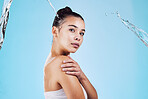 Water splash, skincare and portrait of woman with health, wellness and cleaning isolated on blue studio background. Shower, mockup and cosmetic beauty glow, model in skin care treatment or routine.