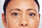 Closeup, portrait and eyes of a mature woman isolated on a studio background for skincare beauty. Wrinkles, treatment and the face of a model for anti aging, facial wellness and care for skin