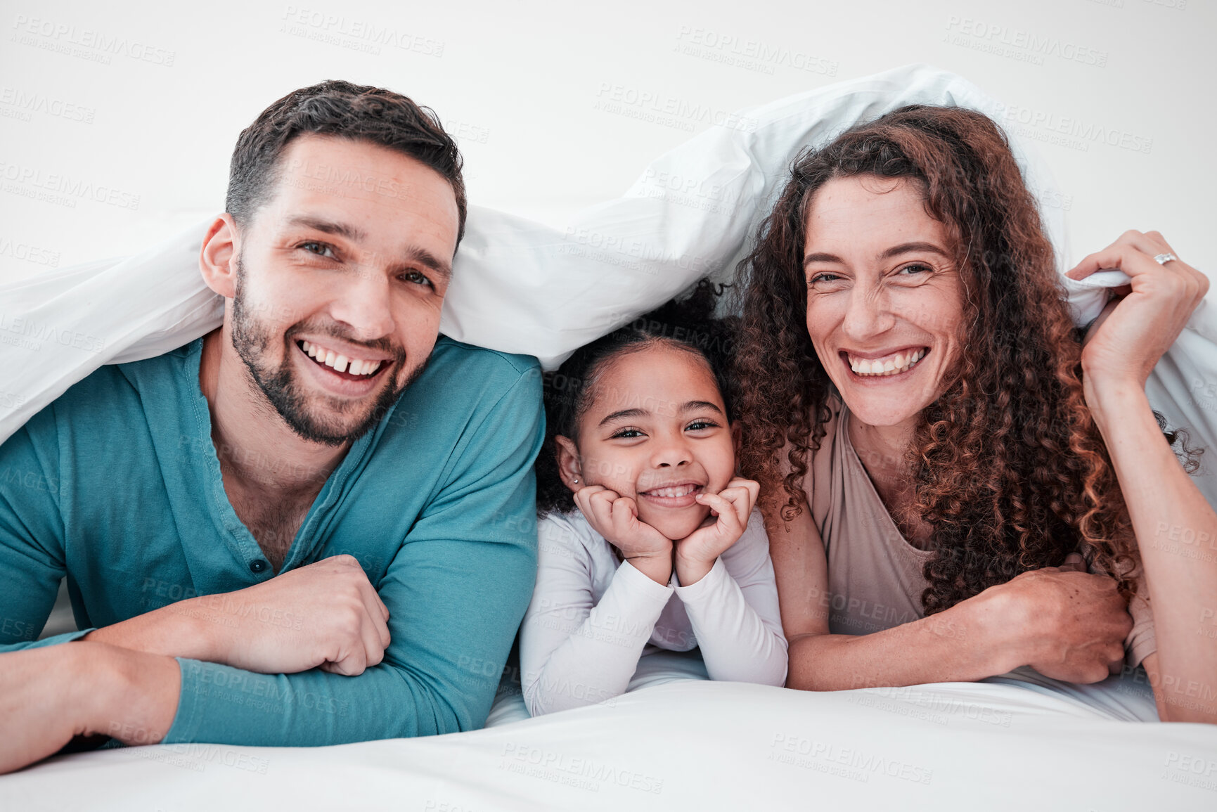 Buy stock photo Family in bed, happy parents and child in portrait, relax and smile together with love and care. Spending quality time under blanket, bonding and relationship, man and woman with young girl at home