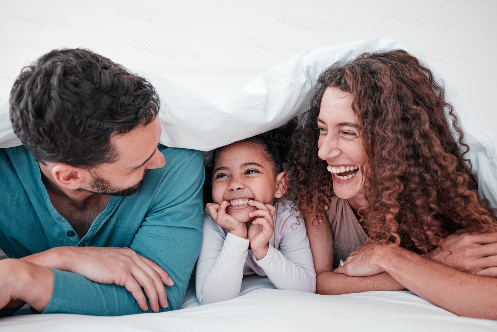 Buy stock photo Family in bed, parents laughing with child and relax with smile under blanket in bedroom with love and care. Spending time together, bonding and relationship, man and woman with young girl at home