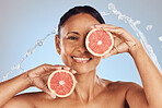 Skincare, portrait and woman with a grapefruit in studio for a natural, beauty and organic face routine. Cosmetic, water splash and mature female model with a citrus fruit isolated by blue background