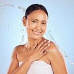 Senior woman, water splash and beauty portrait, hygiene and sustainable skincare for antiaging on blue background. Hand, clean and female smile, eco friendly dermatology and cosmetic care in studio