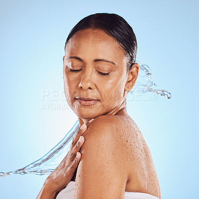 Buy stock photo Skincare, shower and a mature woman with a water splash isolated on a blue background in a studio. Glow, anti aging and a model with hydration, liquid and fluid for skin, grooming and hygiene