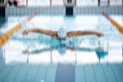 Sports, butterfly or girl training in swimming pool for a race competition, exercise or cardio workout. Blurry swimmer, wellness or healthy woman exercising with fitness speed or motivation in water