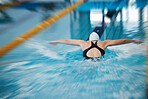 Sports, back or girl training in swimming pool for a race competition, exercise or cardio workout. Blurry swimmer, butterfly or healthy woman exercising with fitness speed or motivation in water