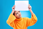 Poster, thinking and face of woman on blue background for announcement, news and information. Advertising, mockup studio and isolated happy girl with paper sign for brand, logo and product placement