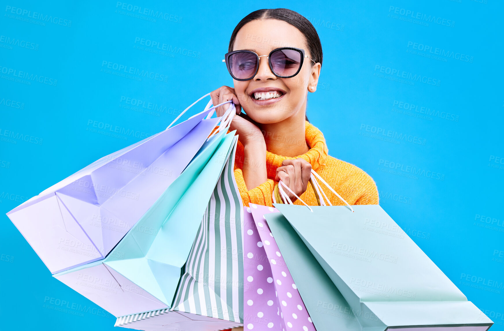 Buy stock photo Retail bags, studio and woman portrait with a smile and happiness from boutique sale. Happy, shopping and female model with store bag and sales choice in isolated blue background with sunglasses