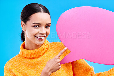 Buy stock photo Speech bubble, happy and portrait of woman pointing to banner in studio for advertising on blue background. Face, smile and girl with poster, mockup and space for social media, announcement or news