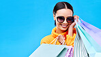 Shopping gift bags, studio and woman portrait with a smile and happiness from boutique sale. Happy, customer and female model with store bag and sales choice in isolated blue background with mockup