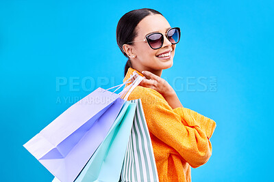 Buy stock photo Shopping bags deal, studio and woman portrait with a smile and happiness from boutique sale. Happy, customer and female model with store bag and sales in isolated blue background with sunglasses