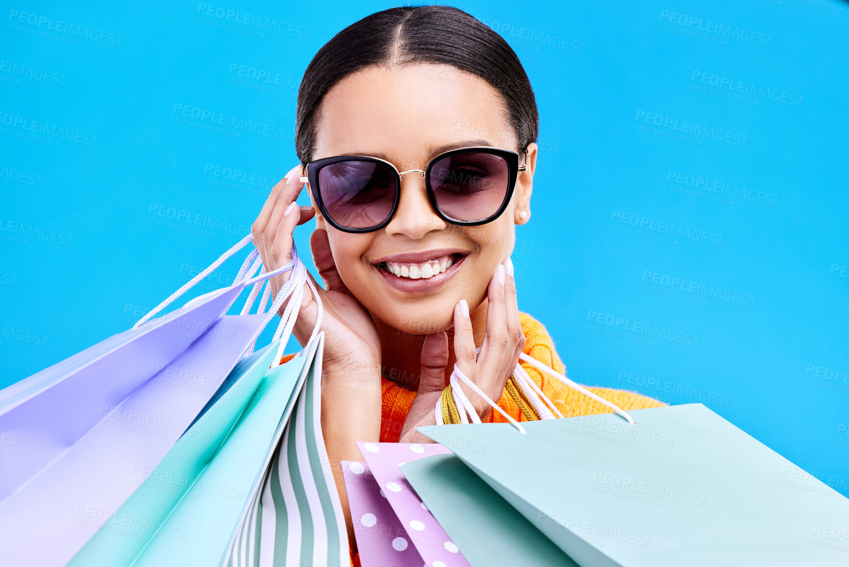 Buy stock photo Shopping bags, studio and happy woman portrait with a smile and happiness from boutique sale. Sunglasses, customer and female model with store bag and sales choice in isolated blue background