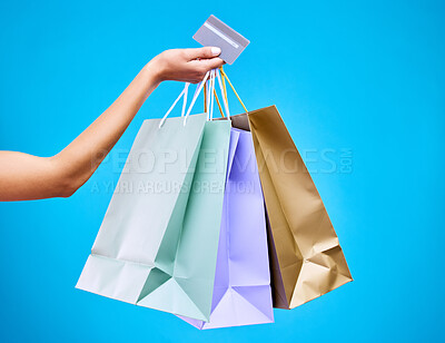 Buy stock photo Woman, hands and shopping bags with credit card for purchase, sale or discount against a blue studio background. Hand of female shopper holding gift bag or presents for banking transaction or buying