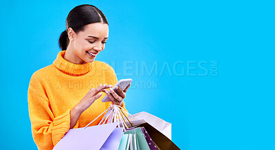 Buy stock photo Happy woman, phone and shopping bags on mockup for purchase, sale or discount against a blue studio background. Excited female shopper smiling on mobile smartphone holding gift bag on copy space