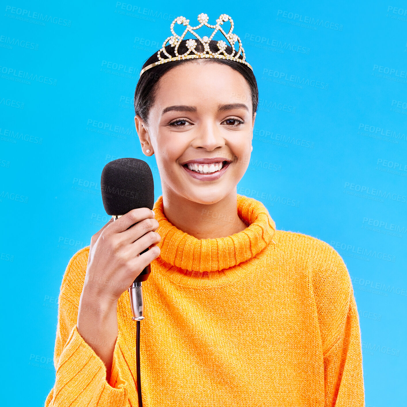 Buy stock photo Woman, crown and microphone in studio portrait with smile for singing, recording or performance by blue background. Happy singer, girl and model with mic for speech, announcement or talk with tiara