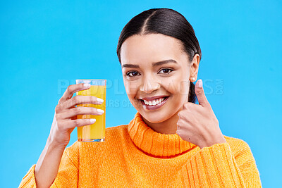 Buy stock photo Happy woman, portrait and thumbs up for orange juice in studio, blue background and yes emoji. Female model, drinking glass and good review of fruit cocktail for nutrition, vitamin c diet and detox
