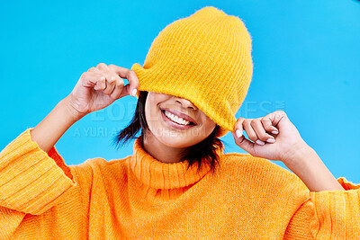 Buy stock photo Fashion, happy and hide with woman and beanie in studio for cover, winter and goofy. Playful, happiness and smile with female and knitted hat isolated on blue background for funny, silly and cool
