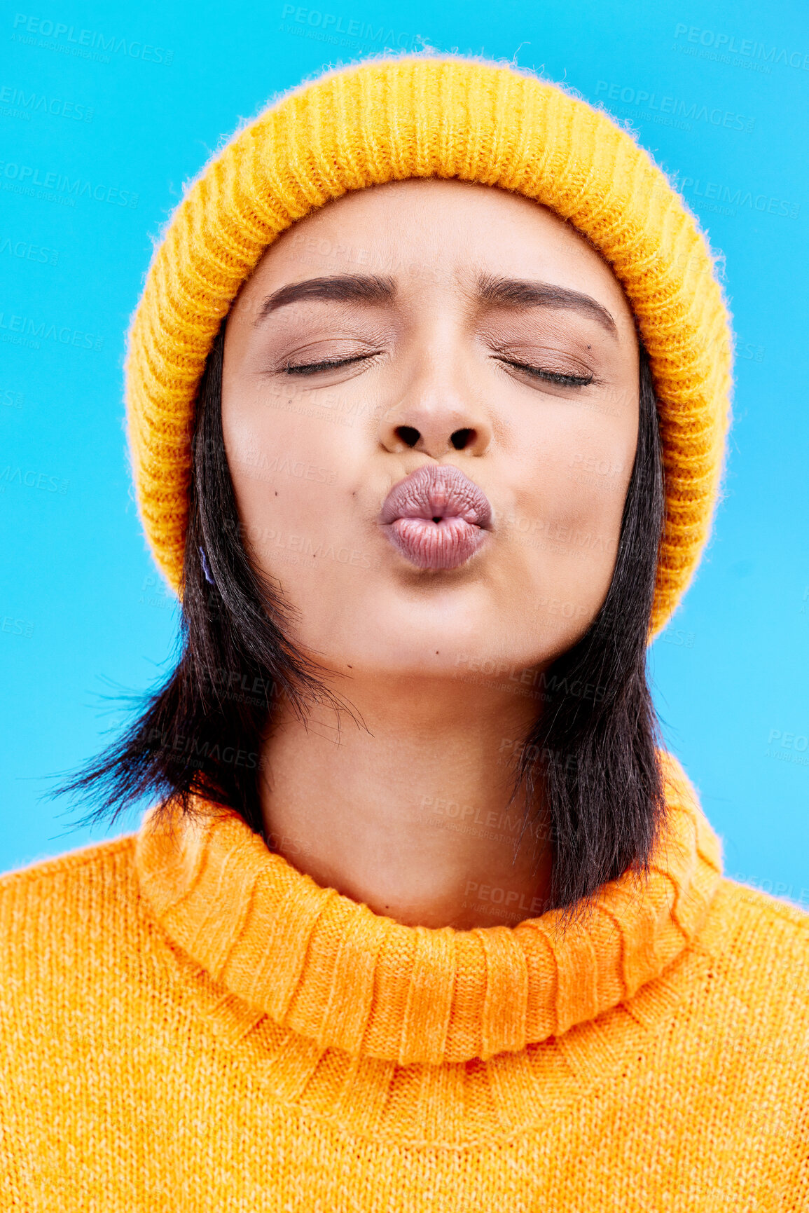 Buy stock photo Portrait of woman in winter fashion with kiss face, beanie and jersey isolated on blue background. Style, flirt and romance, gen z girl in studio backdrop with love and warm clothing for cold weather