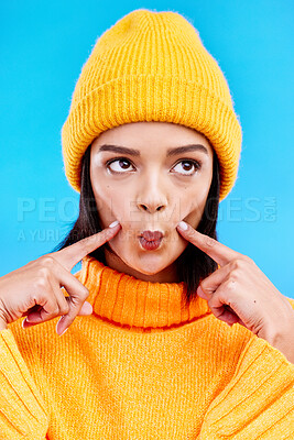 Buy stock photo Goofy woman in winter fashion with comic expression, beanie and fun isolated on blue background. Style, happiness and silly gen z girl in studio with funny face and warm clothing for cold weather.