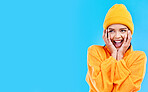 Happiness, excited smile and woman with mockup in studio ready for cold weather with winter hat. Isolated, blue background and mock up with a happy young and gen z person with a beanie and joy