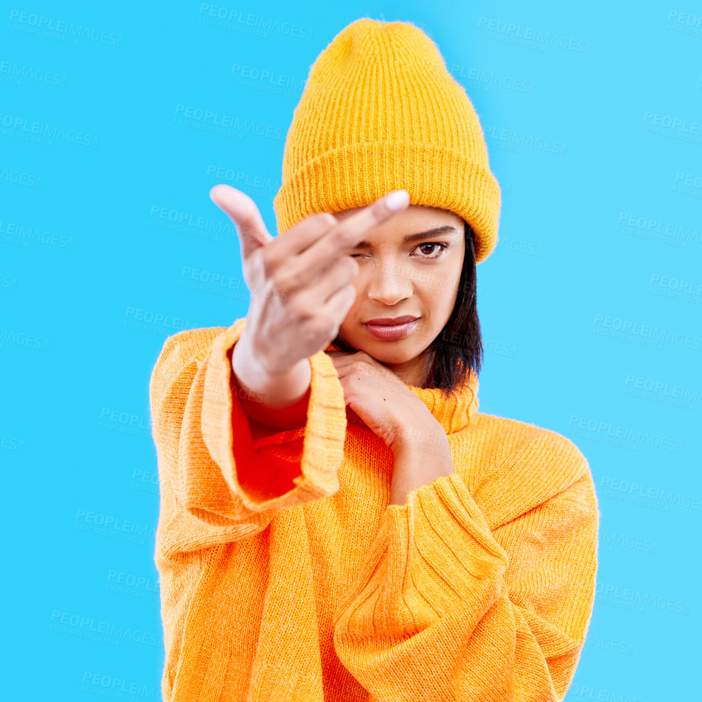 Buy stock photo Portrait, hand gesture and rude with a woman on a blue background in studio wearing a yellow beanie or outfit. Emoji, angry and insult with an attractive young female showing the middle finger
