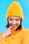 Portrait of woman in winter fashion with happy face, beanie and smile isolated on blue background. Style, happiness and gen z girl in studio backdrop, mockup and flirt, warm clothing for cold weather