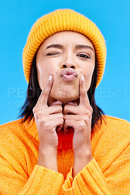Buy stock photo Portrait of woman in winter fashion with kiss, beanie and happiness isolated on blue background. Style, face of happy gen z girl in studio with fun expression and warm clothing for cold weather.