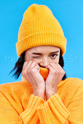 Buy stock photo Portrait of woman in winter fashion with cozy jersey, beanie and wink isolated on blue background. Style, happiness and gen z girl in studio backdrop with mock up and warm clothing for cold weather.