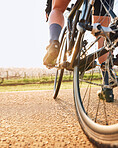 Bicycle closeup, countryside ride and person on a bike with speed for sports race on a gravel road. Fitness, exercise and fast athlete doing sport training in nature on a trail for cardio and workout