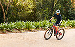 Sports, nature and woman cycling on a bicycle while training for a race, marathon or competition. Fitness, workout and female athlete cyclist doing cardio exercise on a bike on outdoor trail in park.