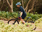 Fitness, cycling and female riding a bicycle while training for a race, marathon or competition. Sports, workout and woman athlete cyclist doing cardio exercise on a bike on an outdoor trail in park.