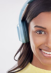 Portrait, headphones and half with a woman in studio on a gray background listening to music. Face, happy and smile with an attractive young female streaming audio using a subscription service