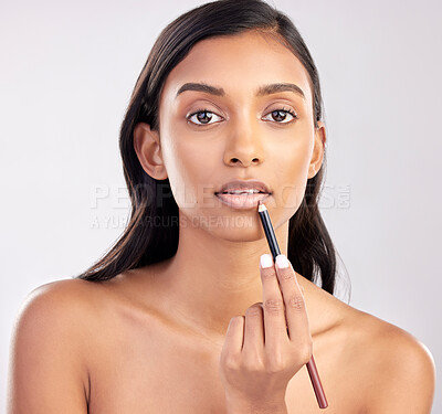 Buy stock photo Woman, face and portrait with makeup and lip liner, beauty and cosmetic product with glow on studio background. Indian female, cosmetics pencil for lips and lipstick with healthy skin and cosmetology