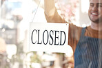 Closed, sign and happy man at shop, store and notice of retail closing time, board and advertisement. Closeup of employee advertising end of business to public, signage or information on glass window