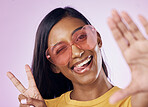 Hand, peace and selfie by indian woman in studio with heart sunglasses, cheerful or fun on purple background. Portrait, v sign and girl gen z fashion influencer smile for profile picture or blog post
