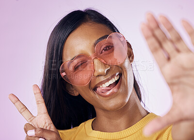 Buy stock photo Selfie, peace and indian woman in studio with heart sunglasses, cheerful or fun on purple background. Portrait, v sign and girl gen z style fashion influencer smile for profile picture or blog post