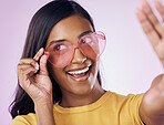 Heart, glasses and selfie by indian woman in studio happy, cheerful and fun on purple background. Sunglasses, pose and female gen z fashion influencer smile for profile picture, photo or blog post