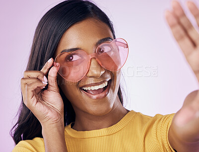 Buy stock photo Heart, glasses and selfie by indian woman in studio happy, cheerful and fun on purple background. Sunglasses, pose and female gen z fashion influencer smile for profile picture, photo or blog post