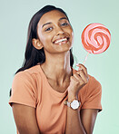 Happy, lollipop portrait and studio woman with candy, junk food or dessert product for delicious snack. Happiness, smile or Indian gen z person with sweets, sucker or sugar treats on green background