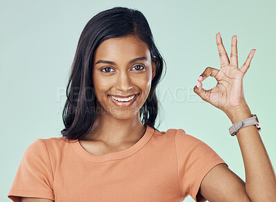 Buy stock photo Portrait, perfect hand gesture and woman in a studio with a positive, confident and happy mindset. Happiness, smile and young Indian female model with a ok sign language isolated by green background.