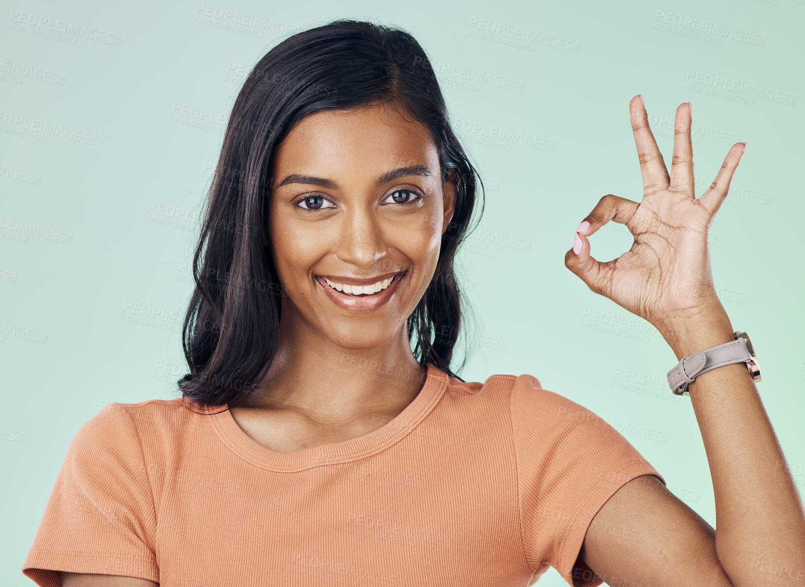 Buy stock photo Portrait, perfect hand gesture and woman in a studio with a positive, confident and happy mindset. Happiness, smile and young Indian female model with a ok sign language isolated by green background.